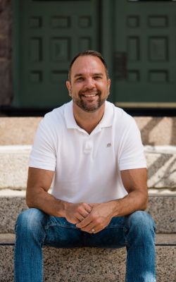 Profile of a man wearing glasses and a suit