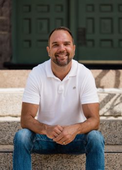 Profile of a man wearing glasses and a suit
