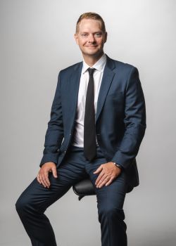 Profile of a man wearing glasses and a suit